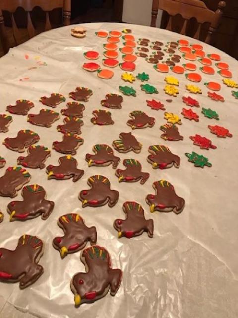 Rows of frosted cookies shaped like turkeys and leaves on a table