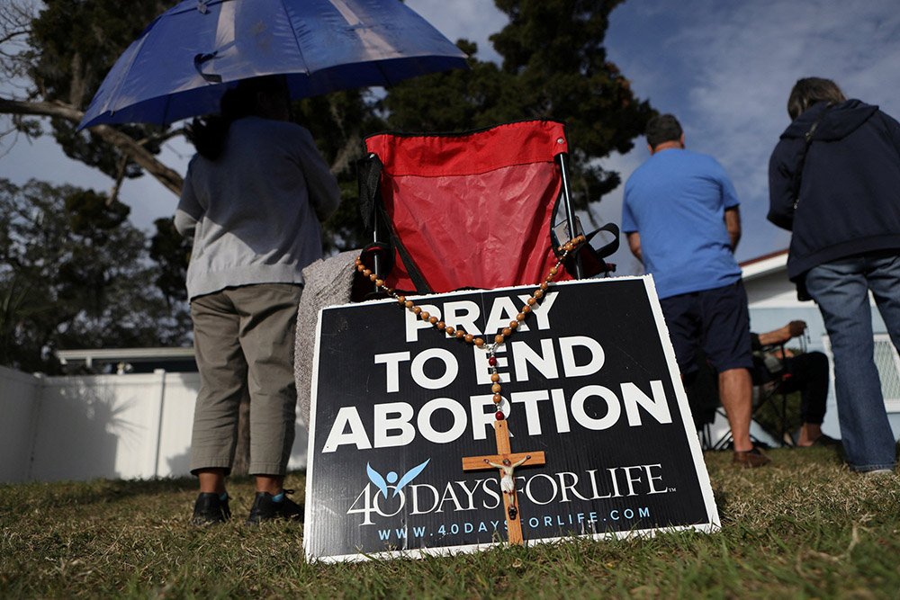 Pro-life activists pray with rosaries Feb. 11 as clients arrive at the Bread and Roses Woman's Health Center, a clinic that provides abortions in Clearwater, Florida. (OSV News/Reuters/Octavio Jones)