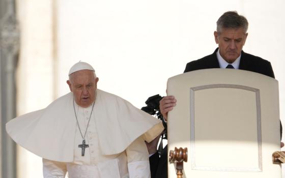 Pope Francis' mozzetta flies out in the wind as he walks beside a white chair