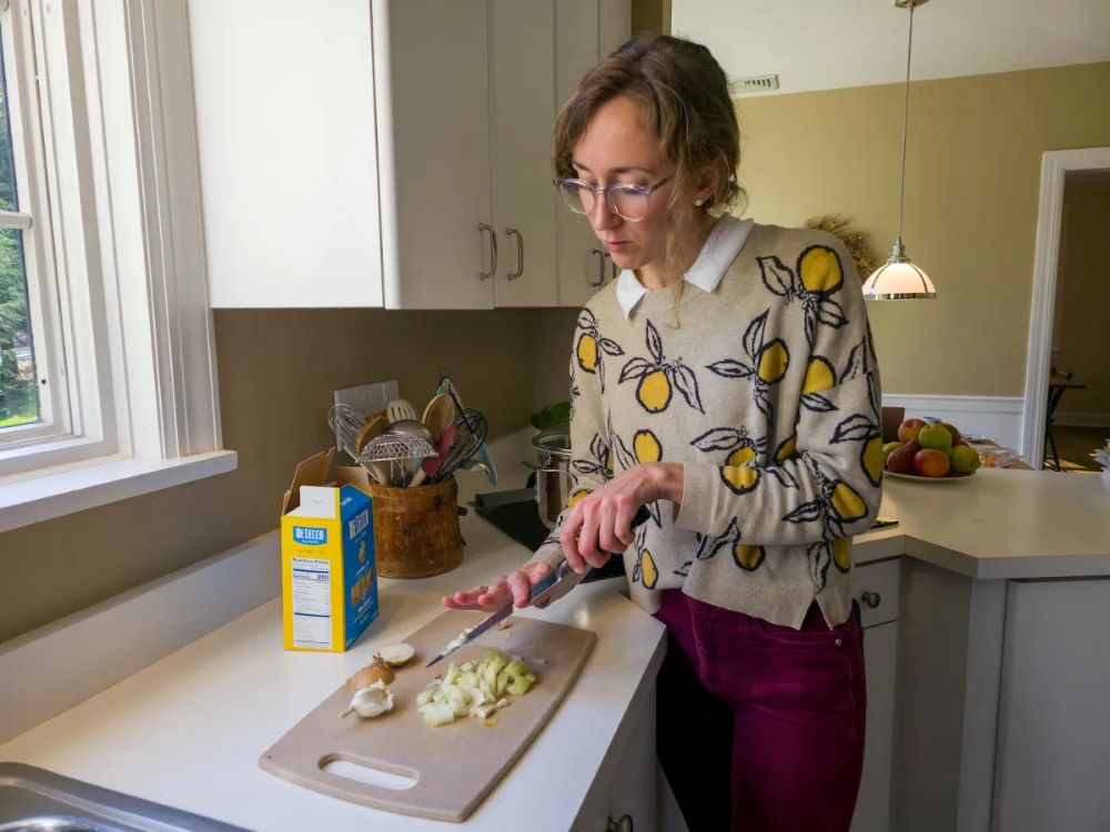 A photo of Caroline Sanders chopping onions and garlic for the "Anything-in-the-Kitchen Pasta" from the cookbook "Perfectly Good Food." (Grist/Haley Saunders)