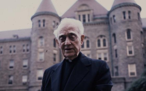 Msgr. John Tracy Ellis, 1905-1992, in front of a stone building