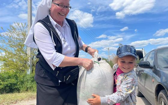 During a recent humanitarian mission to war-torn eastern Ukraine, a child assists Sr. Lydia Timkova carry a bag of supplies, in a village near Mykolaiv. Timkova has traveled across Ukraine to shepherd food and medical supplies to civilians living near the Russian front. (Courtesy of Lydia Timkova)