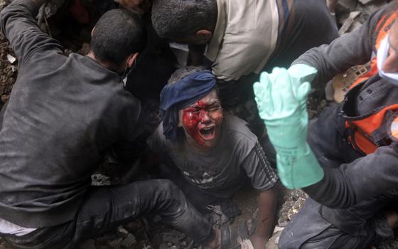 An injured Palestinian boy cries as rescuers try to pull him out of the rubble of a destroyed building after an Israeli airstrike in Bureij refugee camp, Gaza Strip, Nov. 2. (AP/Mohammed Dahman)
