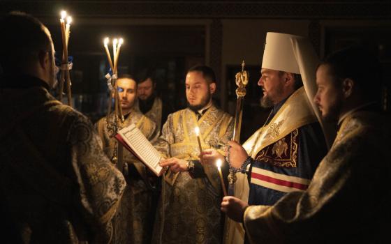 Metropolitan Oleksandr delivers a religious service with clerics inside the Transfiguration of Jesus Orthodox Cathedral during blackout caused by recent Russian rocket attacks, in Kyiv, Ukraine, Saturday, Dec. 3, 2022. A top Orthodox priest in Ukraine's capital says he supports the efforts of President Volodymyr Zelenskyy's government and counter-intelligence agency to end Russian spying and meddling in Ukrainian politics through a Moscow-affiliated church. (AP Photo/Efrem Lukatsky)