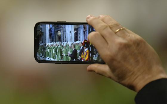 A person uses a smartphone to film as Pope Francis presides over a Mass for the closing of the first session of the synod on synodality in St.Peter's Basilica at the Vatican Oct. 29. (AP/Alessandra Tarantino)